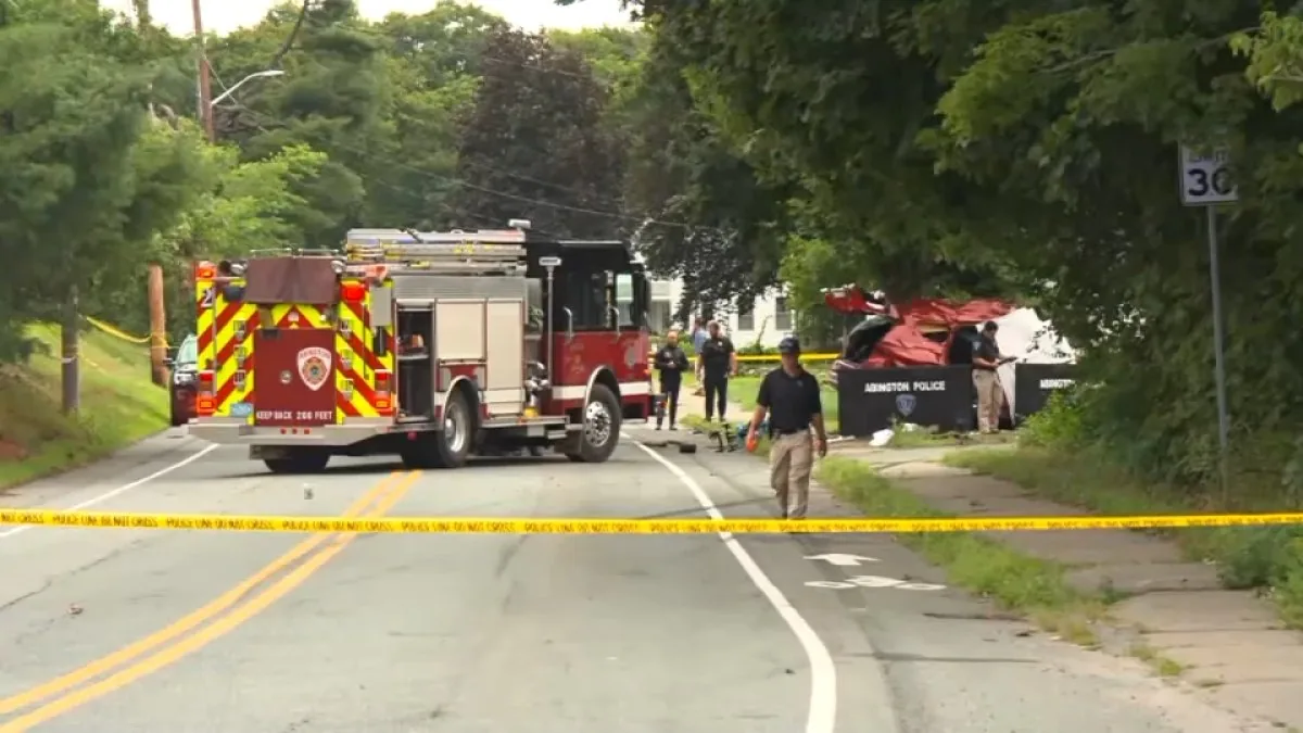 Damaged red SUV off the road beside a tree after a police chase crash in Abington